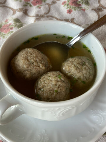 Drei Leberknödel in traditioneller Suppenschüssel mit Henkeln und Untertasse.