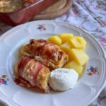 Krautrouladen - Austrian Cabbage Rolls served on a plate with potatoes and sour cream.