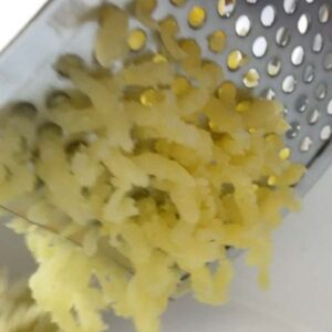 Kartoffel durch Kartoffelpresse drücken