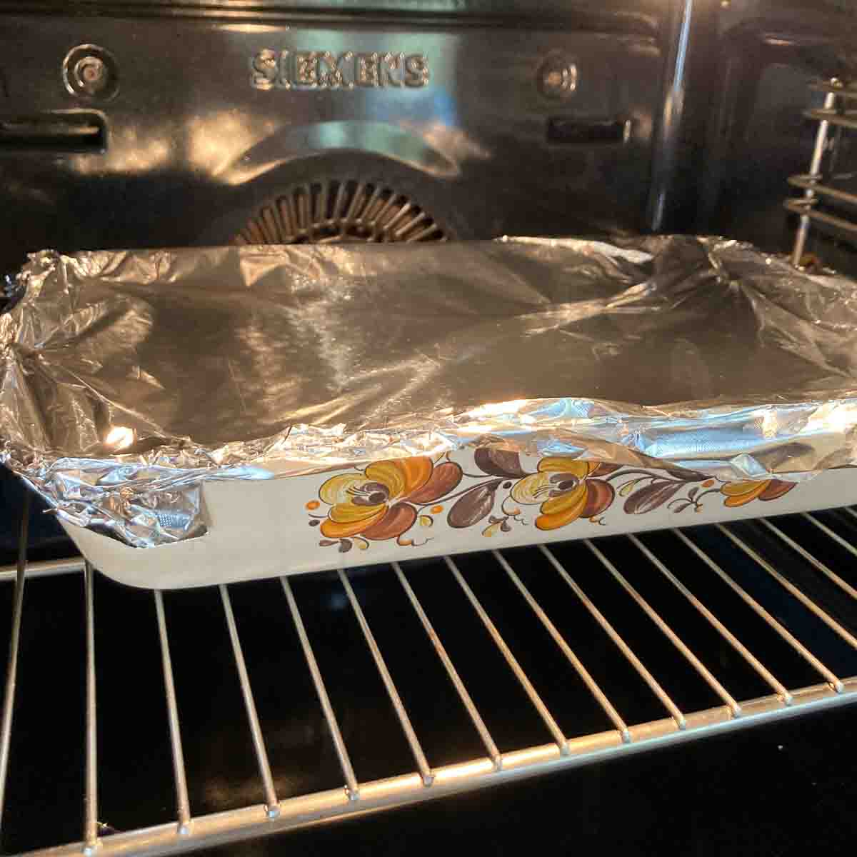 Schinkenfleckerl zugedeckt mit Aluminiumfolie im Ofen - Schinkenfleckerl covered with aluminium foil in oven.