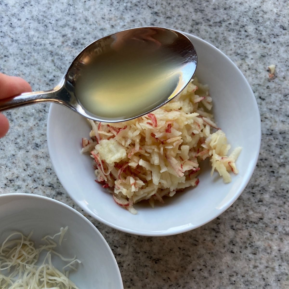 Geriebener Essig in Schüssel mit einem Esslöffel Apfelessig.