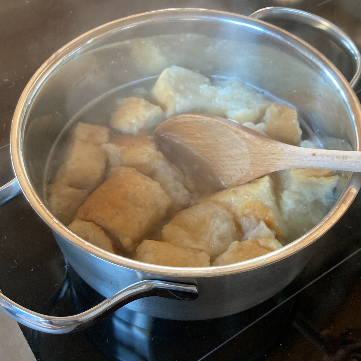 Semmelstücke aufgeweicht in Rindsuppe in Topf.