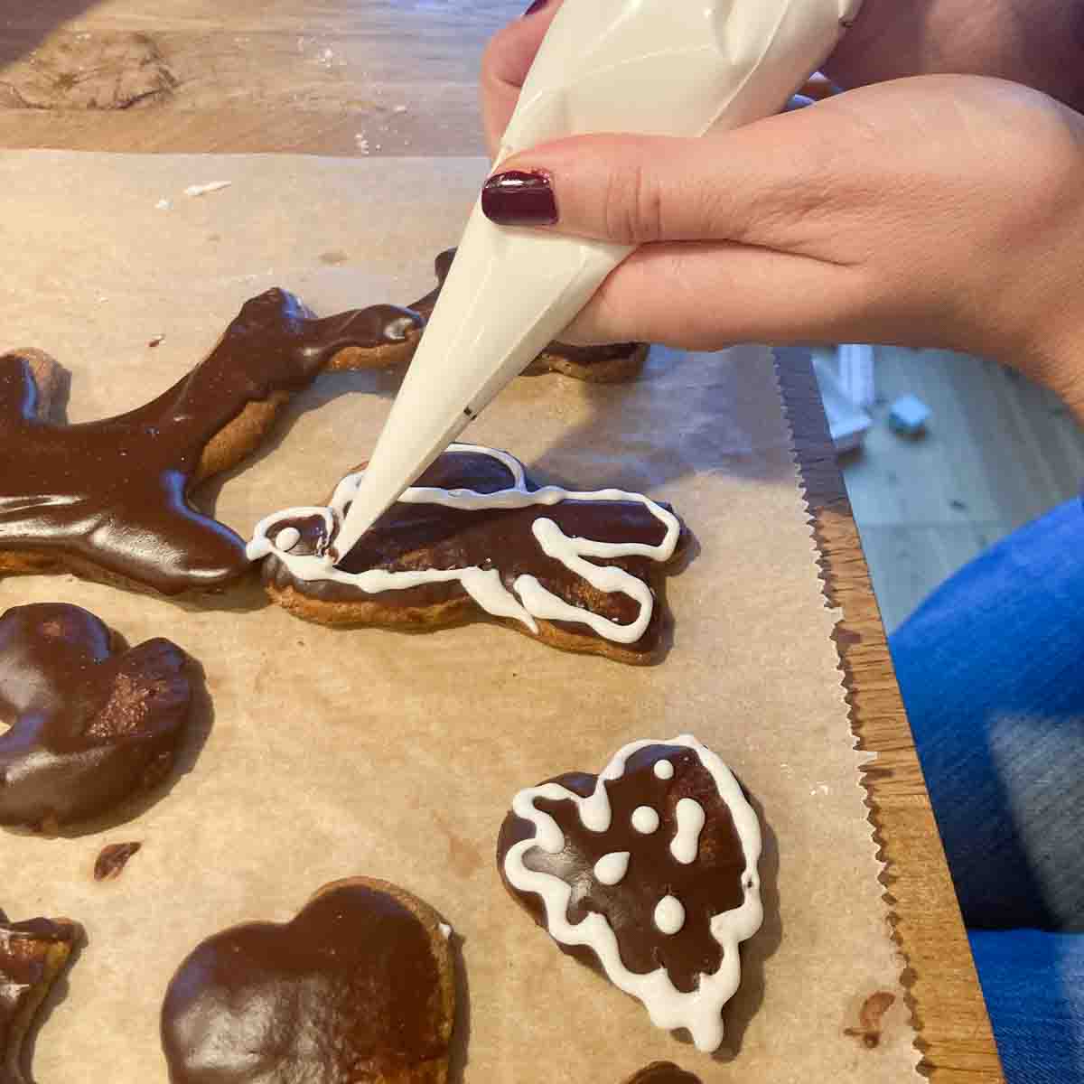 Zuckerguss wird mit Spritzbeutel auf Lebkuchen gefüllt. 