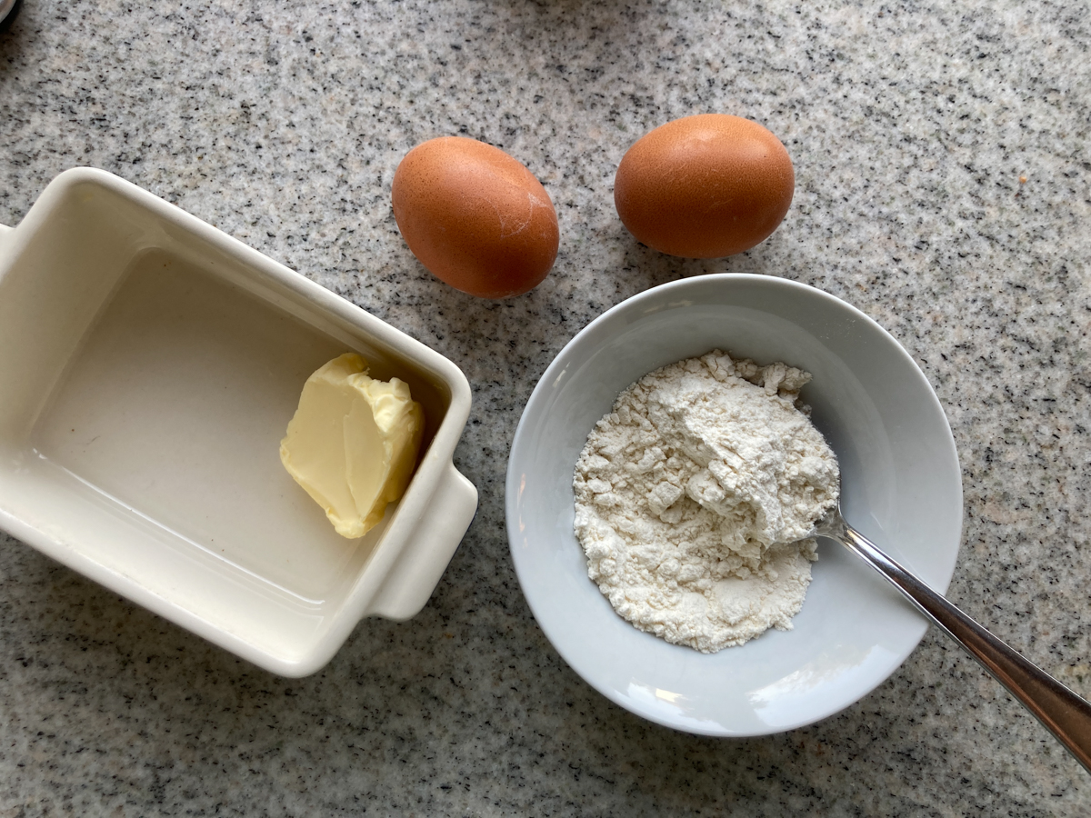 Zutaten für Biskuitschöberl auf Arbeitsfläche: Butter, zwei Eier, Mehl.