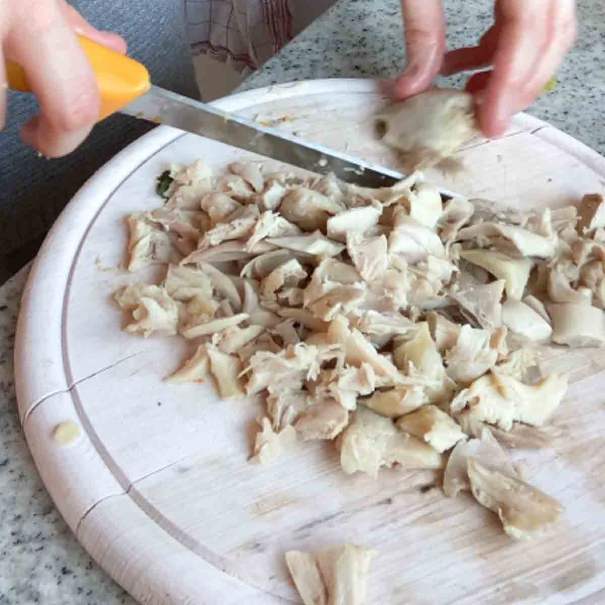 Klein geschnittenes Hühnerfleisch auf Küchenbrett.