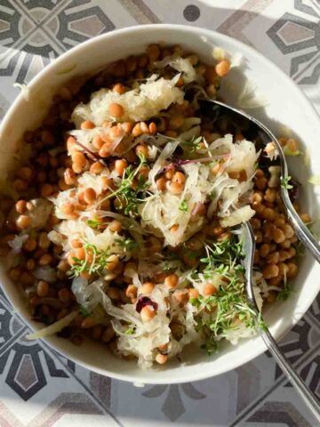 Sauerkrautsalat mit Apfel und Linsen in Schüssel auf gemusterter Fliesenoberfläche. | Sauerkraut Salad.