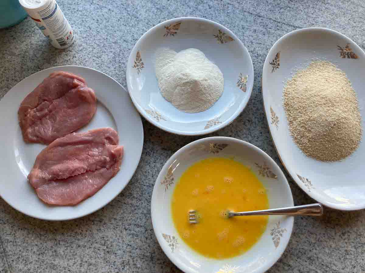 Panierstraße für Wiener Schnitzel: vorbereitete Teller mit Mehl, verquirrltem Ei und Bröseln.