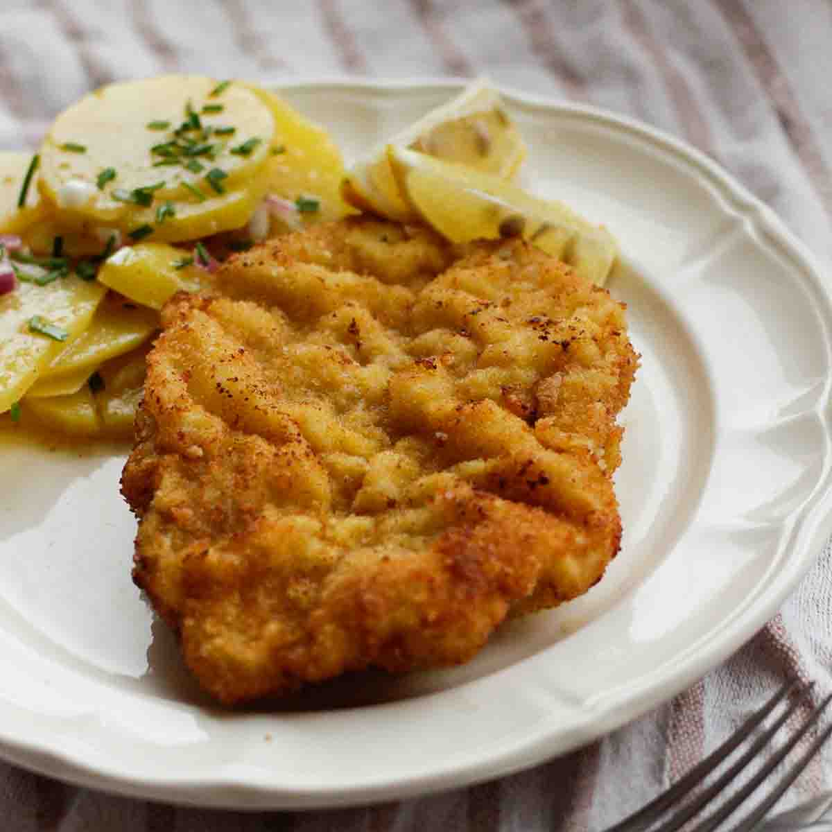 Wiener Schnitzel angerichtet mit Kartoffelsalat und Zitrone.