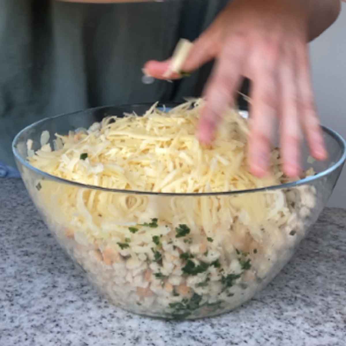 All ingredients being kneaded in a bowl with hands.