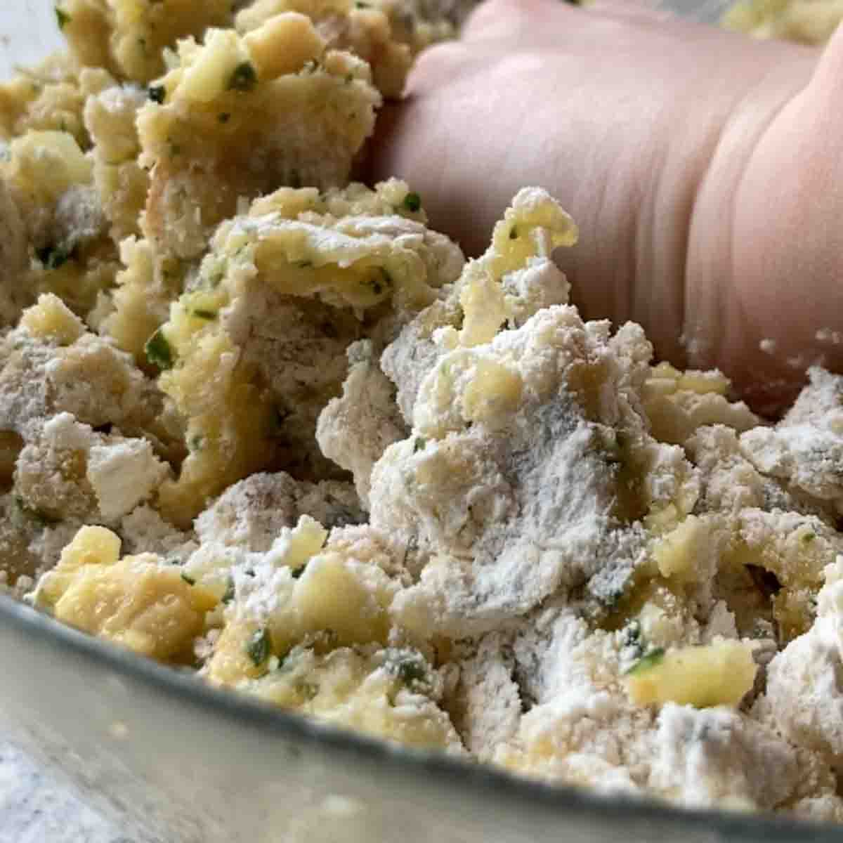 All ingredients being kneaded in a bowl with hands.