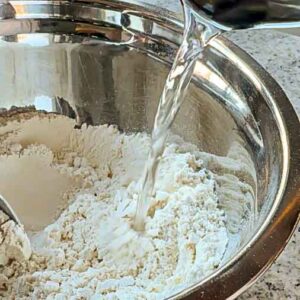 Kochendes Wasser wird zu Mehl in Schüssel gegossen.