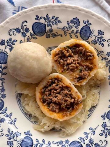 Knödel aus Mehlteig auf blaum geblümtem nostalgischem Teller angerichtet.