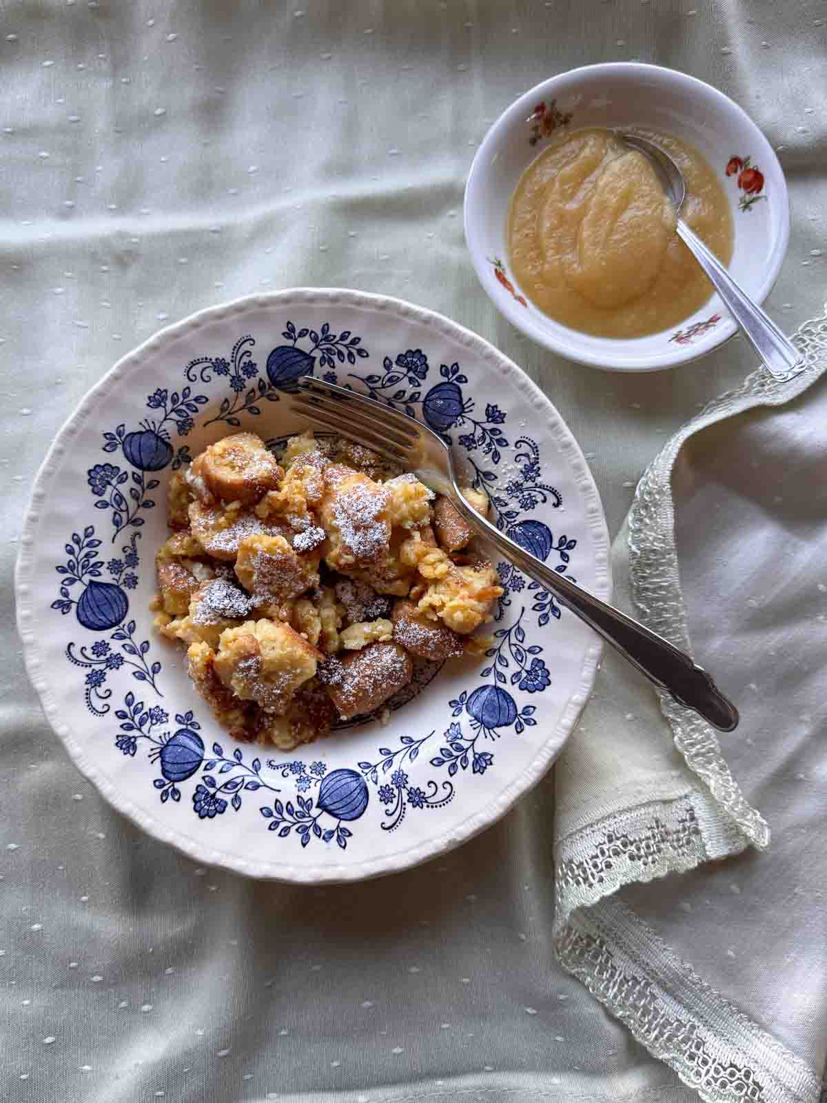 Semmelschmarrn auf blau geblümtem Teller, Apfelmus in kleiner Schüssel.