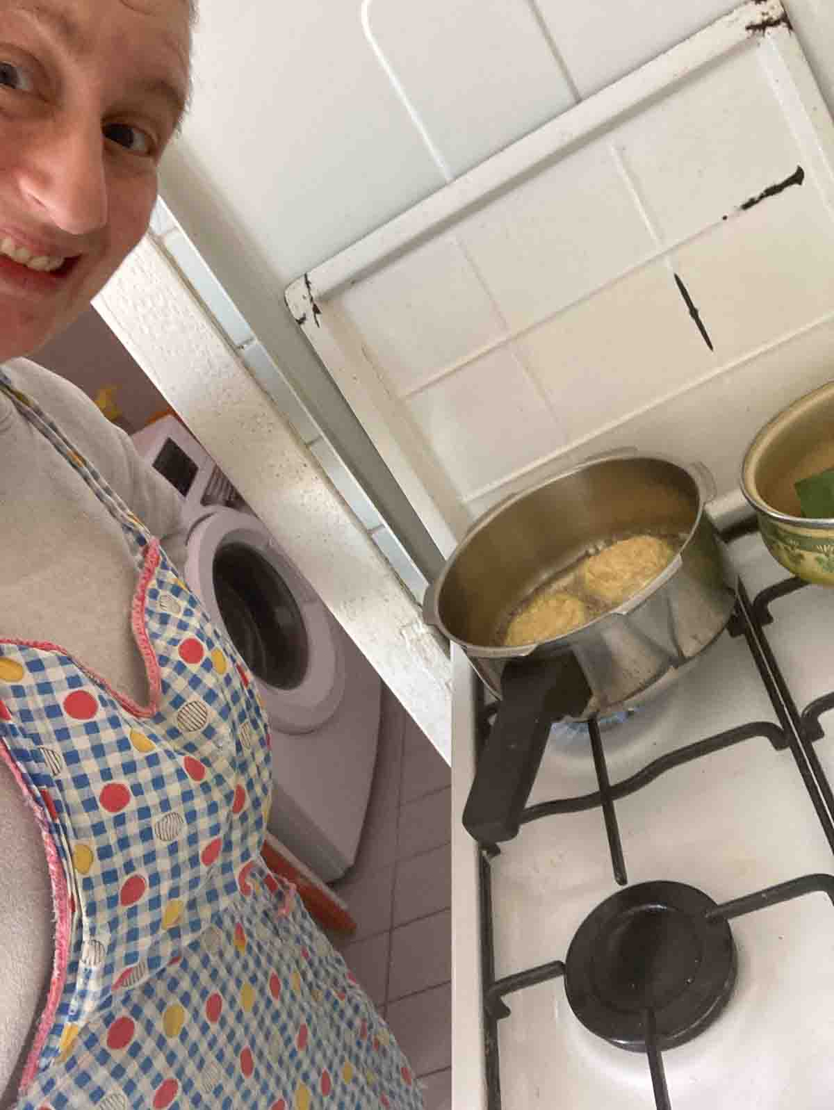 Angelika mit Oma-Schürze beim herausbacken von Erdäpfelpuffern an Omas Gasherd.