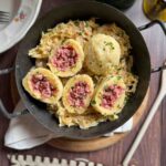 Selchfleischknödel auf Sauerkraut in gusseiserner Pfanne.