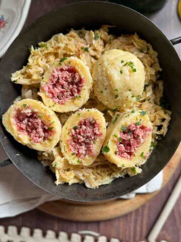 Selchfleischknödel auf Sauerkraut in gusseiserner Pfanne.