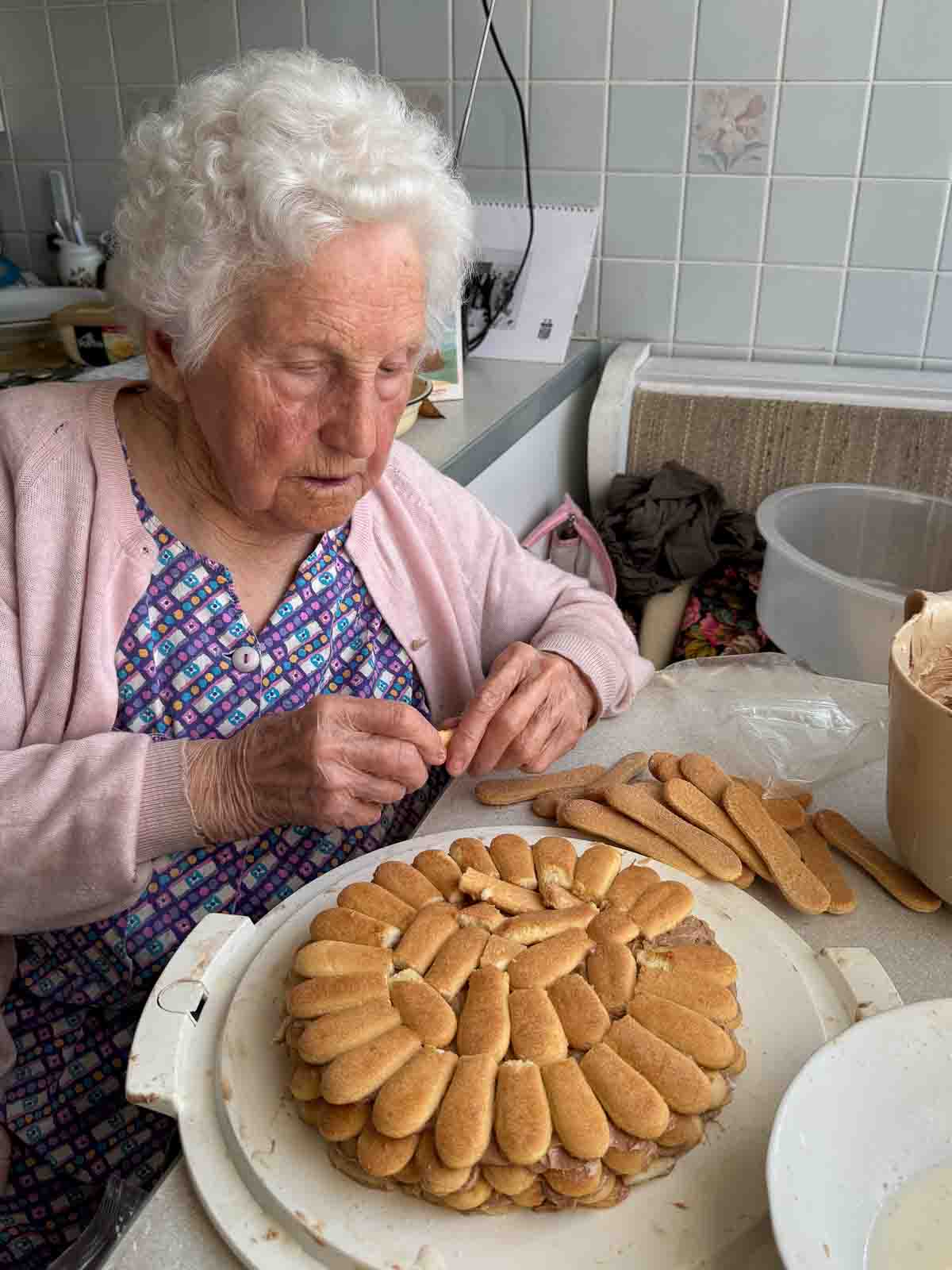 Oma beim Auflegen der Biskotten für die Biskottentorte.