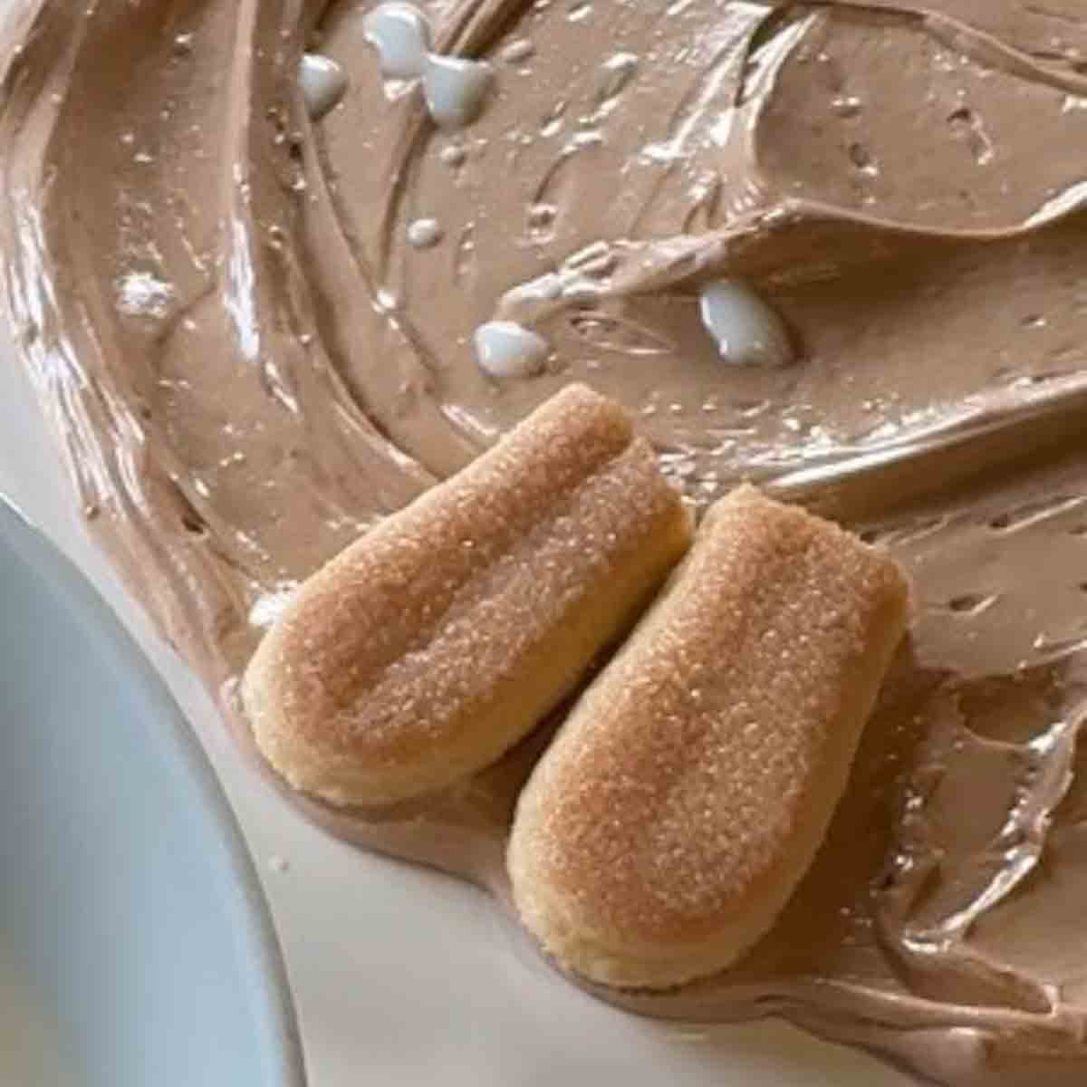 Unterste Schicht der Creme für die Biskottentorte auf Tortenteller verstrichen