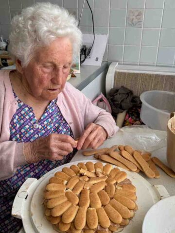 Oma beim Auflegen der Biskotten für die Biskottentorte.