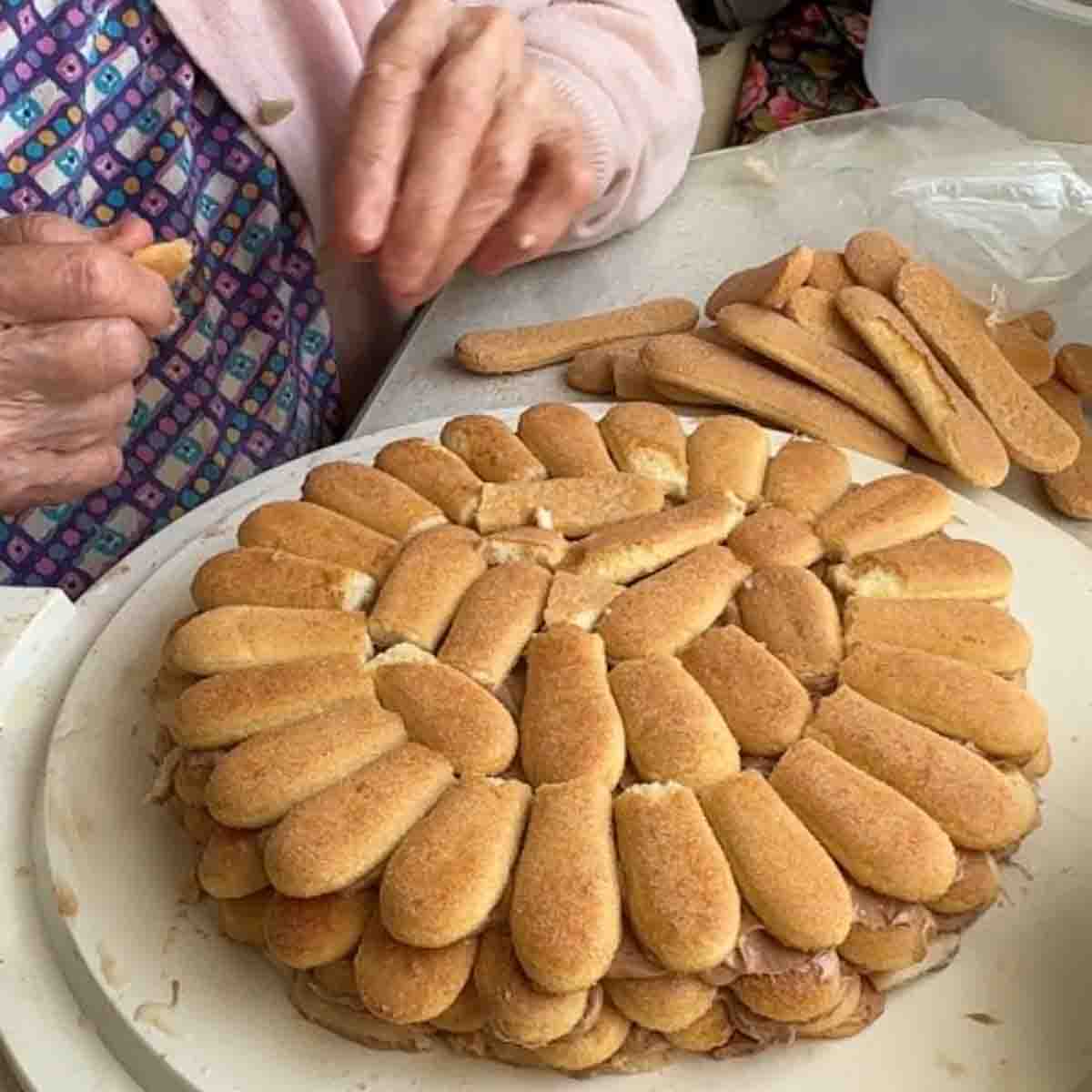 Oma beim Auflegen der Biskotten für die Biskottentorte.